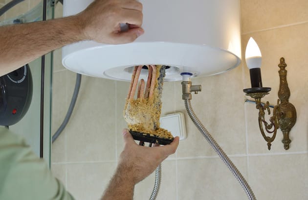 Technician removing mineral buildup from a water heater in Albany