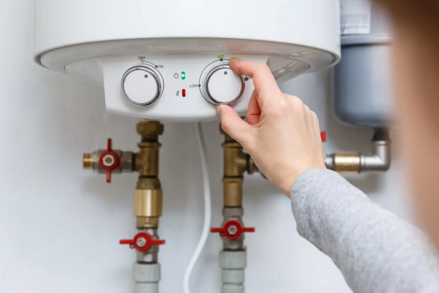 Homeowner adjusting the temperature controls on a water heater in Albany